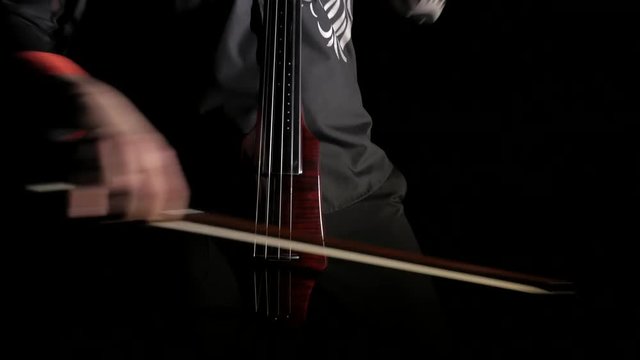 hand of a man playing an electric cello on a black background, close-up of strings, bow and fingerboard, isolated