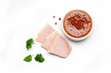 sliced ham pieces and a Cup of ketchup sauce next to parsley leaves and pepper red peas