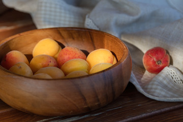 The ripe apricots, juicy fresh yellow with red outflow, which grew on the Azerbaijani earth in a wooden cup in beams of the sunset sun. Macro.