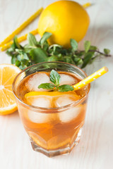 Refreshing citrus lemonade, summer drink. Ice tea with fresh lemon and mint on wooden background. Refreshment beverage concept.