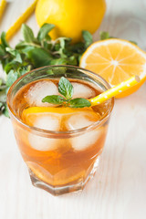 Refreshing citrus lemonade, summer drink. Ice tea with fresh lemon and mint on wooden background. Refreshment beverage concept.