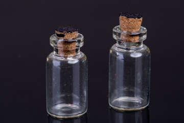 empty small glass bottles with a cork closure on a black background