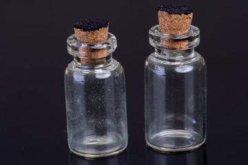empty small glass bottles with a cork closure on a black background with text space