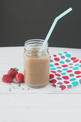 Strawberry smoothie with baby spinach, fresh strawberries and chia on a white wooden table. Superfoods, detox, diet, health, vegetarian food concept.