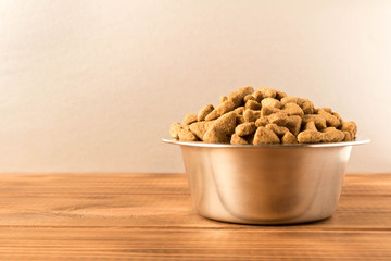 Bowl with dog food on a wooden table. Close up.