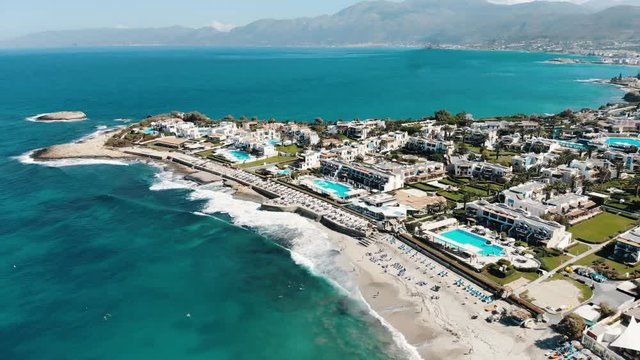 Drone Aerial of Luxury Hotels Pools and Sandy Beach in Anissaras Near Hersonissos on Famous Historic Crete Island Greece With Mediterranean Sea Waves on Sunny Summer Day