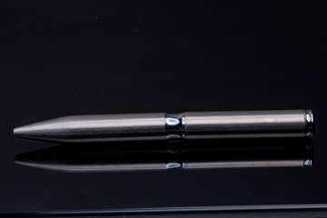 silver ballpoint pen on black reflective background