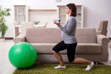 Aged pregnant woman doing exercises at home 