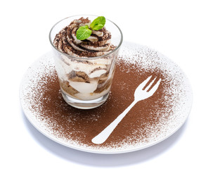 Classic tiramisu dessert in a glass on plate with fork silhouette isolated on a white with clipping path