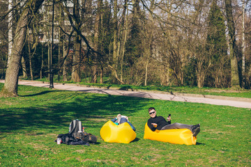 two men friends laying on yellow inflatable mattress reading books surfing internet