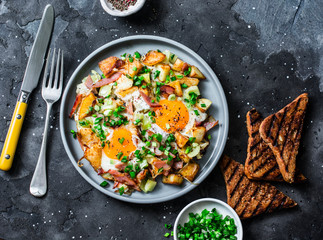 Potatoes, ham, eggs breakfast hash on a dark background, top view. Delicious, nutritious breakfast,...