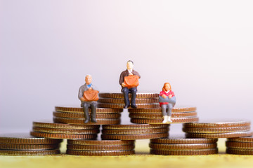 Fototapeta na wymiar Miniature people: Elderly people sitting on coins stack. Retirement planning. money saving and Investment. Time counting down for retirement concept.