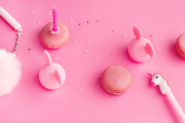 School stationery with unicorn pen,fur, macaroons on a pink background. Back to school creative table desk. Minimal food bakery concept. Flat lay top view with copy space -