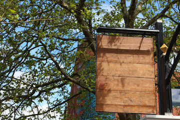 A blank wooden pub sign, add your own text.  Copy space.  Urban and natural background.