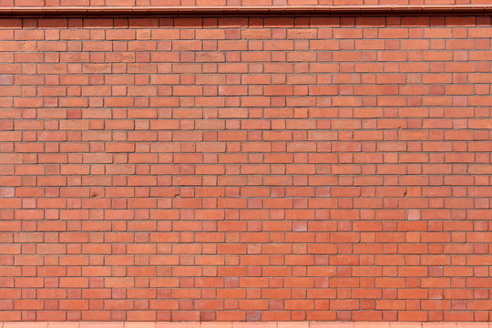 Fototapeta A photograph of a terracotta brick wall. Background texture, copy space, add your own text.  Red bricks in sunlight.