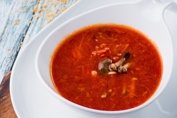 Red borsch of beets, vegetables and meat, with sour cream in a white plate on a blue rustic wooden background, in a beautiful composition. Homemade Russian, Ukrainian national soup. Close up. Space