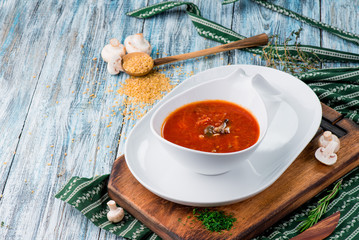 Red borsch of beets, vegetables and meat, with sour cream in a white plate on a blue rustic wooden background, in a beautiful composition. Homemade Russian, Ukrainian national soup. Close up. Space