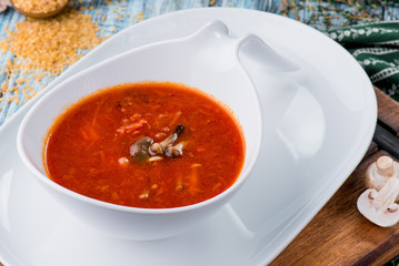 Red borsch of beets, vegetables and meat, with sour cream in a white plate on a blue rustic wooden background, in a beautiful composition. Homemade Russian, Ukrainian national soup. Close up. Space