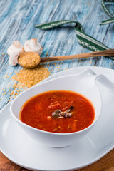 Red borsch of beets, vegetables and meat, with sour cream in a white plate on a blue rustic wooden background, in a beautiful composition. Homemade Russian, Ukrainian national soup. Close up. Space