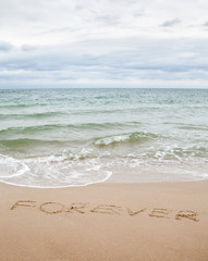 Fototapeta na wymiar Word forever written on the sand