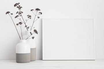 Mock up frame and dry twigs in vase on book shelf or desk. White colors..