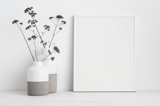 Frame and dry twigs in vase on book shelf or desk. Mockup.
