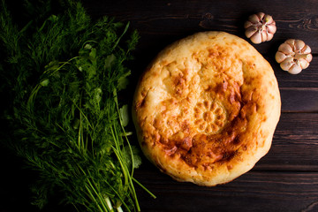 Traditional bread pita on the dark wood table with herbs and garlic. Homemade baking recipe. Top view. Menu.