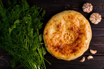 Traditional bread pita on the dark wood table with herbs and garlic. Homemade baking recipe. Top view. Menu.