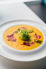 beautifully decorated pumpkin cream soup in a white plate isolated on a white background. top view. flat lay. close-up. light background. space. 