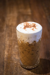 Iced cappuccino coffee in glass on wooden table.