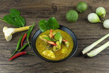 Green curry (Kaeng kheiyw hwan) with Thai food for steamed rice or rice noodles. chicken green curry is thai food very popular on dark wooden background. top view