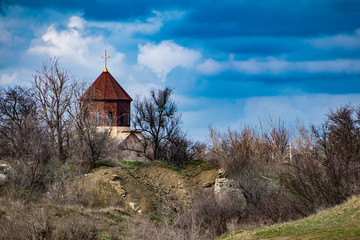 New unfinished Church among the vegetation and dry grass, in the spring with a blue cloudy sky. Dome with cross at the top. Interesting and unusual landscape in the Rostov region