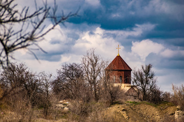 New unfinished Church among the vegetation and dry grass, in the spring with a blue cloudy sky. Dome with cross at the top. Interesting and unusual landscape in the Rostov region