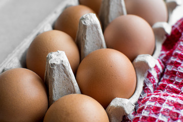 Chicken eggs in the carton with kitchen towel. Close-up. 
