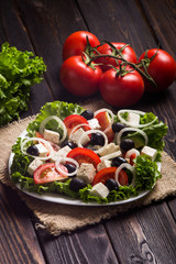 Fresh vegetable salad with cheese, onion, tomatoes, cucumber and vegetables on wooden background. Greek salad. Menu photo design. Side view. 
