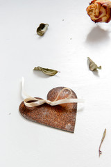 Symbol der Liebe: rostiges Herz, Blätter und getrocknete Rose vor weißem Hintergrund