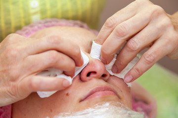 A young girl is lying on a couch during cosmetic procedures with a mask on the face above which...