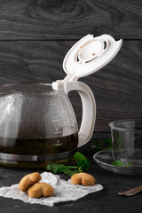 Tea with mint leaves and sweet coockies. Perfect choose for breakfast. Coockies on the white baking paper. Dark stone table for background, horizontal view