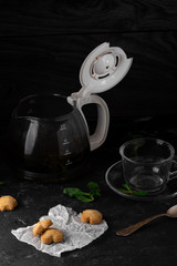 Tea with mint leaves and sweet coockies. Perfect choose for breakfast. Coockies on the white baking paper. Dark stone table for background, horizontal view