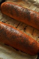 Freshly baked homemade sweet poppy seed rolls lying on baking paper.