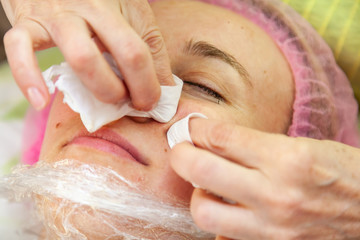 A young girl is lying on a couch during cosmetic procedures with a mask on the face above which...