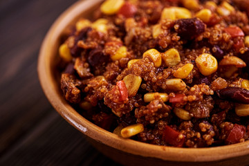 Mexican quinoa warm salad, chili, vegetarian food on dark wood background. Selective focus