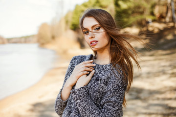 Natural beauty an attractive cute young girl, a portrait in a warm sweater on the bank of the river...
