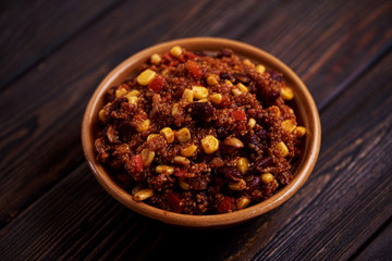 Mexican quinoa warm salad, chili, vegetarian food on dark wood background.