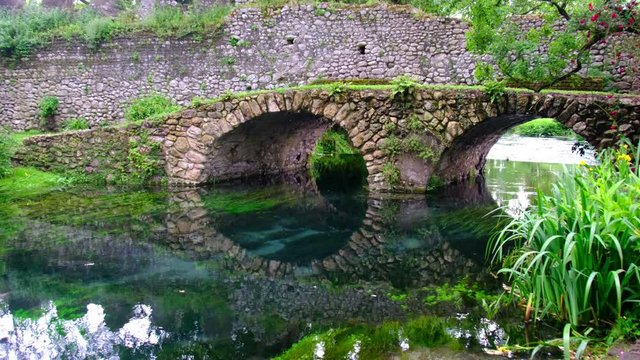 medieval stone bridge in eden colourful garden vibrant with roses and river