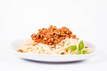 Spaghetti bolognese on a plate decorated with fresh basil in a white background