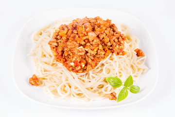 Spaghetti bolognese on a plate decorated with fresh basil in a white background