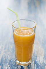 Orange juice glass with straw on blue wooden background aqua