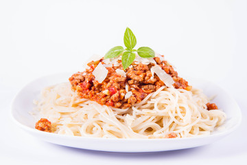 Spaghetti bolognese on a plate decorated with parmesan  cheese and fresh basil in a white background