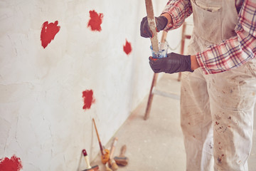 Working woman plastering / painting walls inside the house.